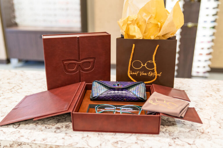 Brown custom glasses box, leather glasses case, and gift bag with gold accents, branded for Sweet View Optical, arranged neatly.