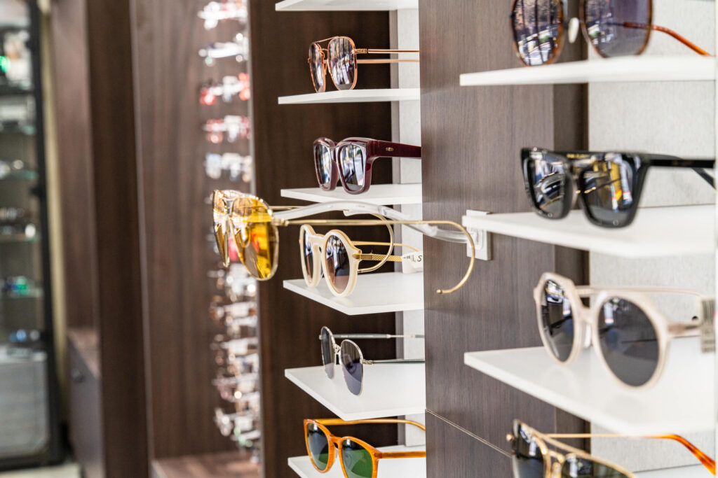 Designer glasses in various colors displayed on sleek shelves, showcasing diverse styles and vibrant frames in a modern setting