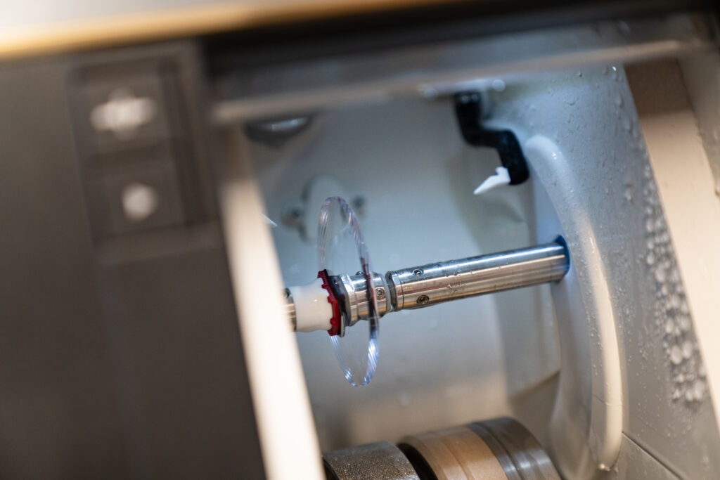 Machine crafting a glasses lens, showcasing precision technology in the lens-making process within an optical lab.